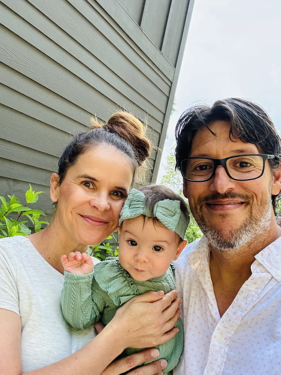 A family portrait shared by Spica Homes, with two parents holding their young child outdoors